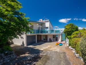 a large white house with a balcony and a driveway at Bay Breeze - Stephens Bay, Kaiteriteri Home in Kaiteriteri
