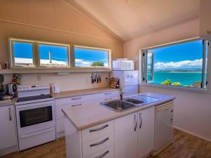 a kitchen with white appliances and a large window at Bay Breeze - Stephens Bay, Kaiteriteri Home in Kaiteriteri