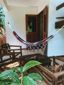 a hammock in a room with two chairs and a table at Chez Max Pousada in Morro de São Paulo