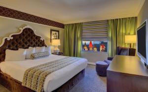 ein Hotelzimmer mit einem großen Bett und einem Schreibtisch in der Unterkunft Excalibur in Las Vegas