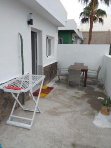 un patio con 2 sedie, un tavolo e una parete bianca di CASA PARAISO a Corralejo