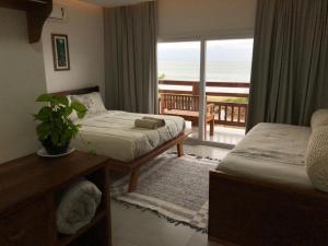 a bedroom with two beds and a balcony with the ocean at Pousada Casa Albatross in Penha