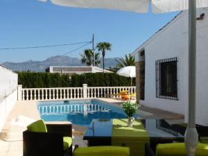 a swimming pool with chairs and a table and an umbrella at Annette in Albir