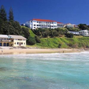 a building on a hill next to a beach at Pacific Hotel Yamba in Yamba