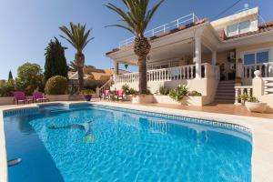 - une piscine en face d'une maison avec des palmiers dans l'établissement Bella Vida Alfaz, à L'Alfàs del Pi