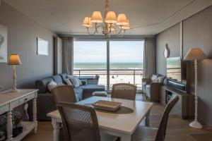 a living room with a table and a living room with a view at Res Helix 1slp kamer app Zeezicht en Parking in Middelkerke