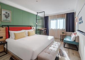 um quarto com uma grande cama branca e um sofá em Campanile Shanghai Bund Hotel em Xangai