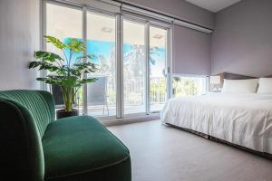1 dormitorio con cama, silla verde y ventana grande en 墾丁後灣 藍水軒海景民宿, en Checheng