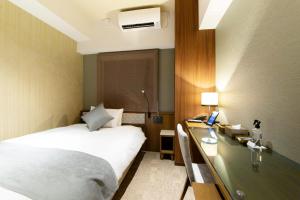 um quarto de hotel com uma cama e uma secretária em HOTEL HILLARYS Shinsaibashi em Osaka