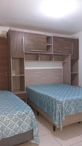 a bedroom with two beds and wooden cabinets at Residencial Costa do Encanto in Penha