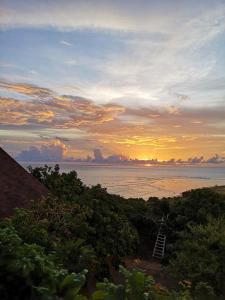 a view of the ocean at sunset with a ladder at Boa Hill Surf House in Nembrala
