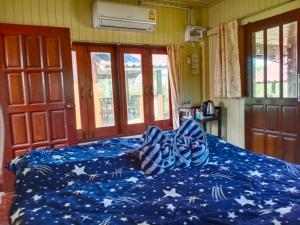 Una cama con un edredón azul con estrellas. en บ้านในสายหมอกบุญแจ้งโฮมสเตย์ en Khao Kho