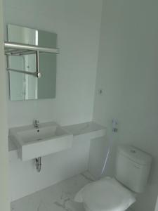 a white bathroom with a toilet and a sink at Diva Residence in Yogyakarta