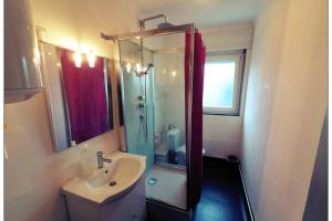 een badkamer met een douche, een wastafel en een wastafel bij Appartement complet in Stiring-Wendel