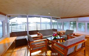 a room with a table and chairs and windows at Soma House Boat in Alleppey