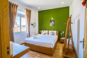 a bedroom with a bed with a green wall at Jessy's Green House Da Lat in Da Lat