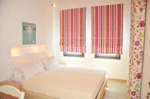 a bedroom with a white bed and two windows at Kleopatra Villas - Seaside Suites in Kolios