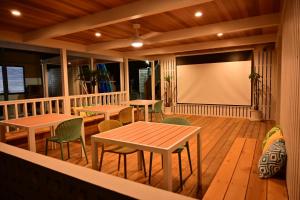 a screened porch with tables and a projection screen at Zeus House in Nishinoomote