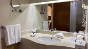 un bagno con un lavandino e un grande specchio di Golden Tulip Nizwa Hotel a Nizwa