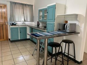 uma cozinha com armários azuis e um balcão com bancos em Plum Cottage em Nelspruit