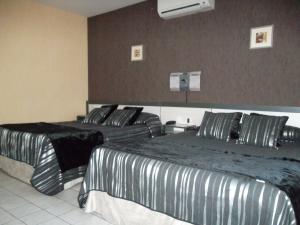2 camas en una habitación de hotel con rayas blancas y negras en Le Médicis, en Roussillon en Isère