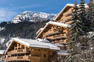 duży drewniany budynek z śniegiem na dachu w obiekcie Le Roc Des Tours w mieście Le Grand-Bornand