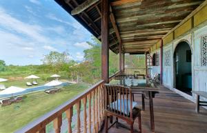 einen Balkon eines Hauses mit einem Tisch und Stühlen in der Unterkunft Temple Tree Resort in Pantai Cenang