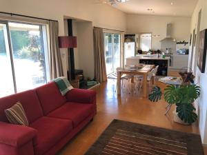 a living room with a red couch and a table at Nikau’s on Palmer in Foxton Beach