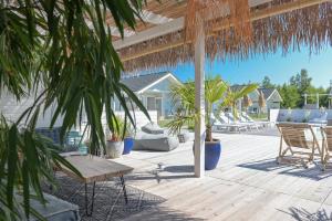 a patio with chairs and tables and palm trees at Pastelowe Domki Wicie in Wicie