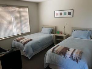 een slaapkamer met twee bedden en een raam bij Nikau’s on Palmer in Foxton Beach