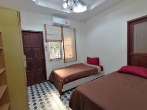a bedroom with two beds and a window and a door at Pool Villa Armthong Home in Ban Nong Toei
