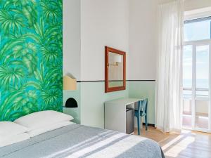 a bedroom with a bed and a desk with a mirror at Hotel Riviera in Anzio