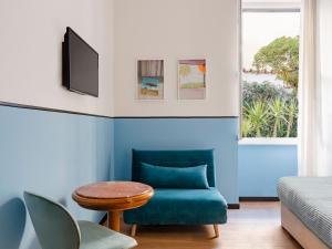a blue living room with a blue chair and a tv at Hotel Riviera in Anzio
