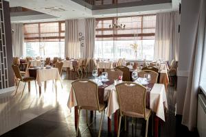 a dining room with tables and chairs and windows at Parus Hotel in Lyskovo