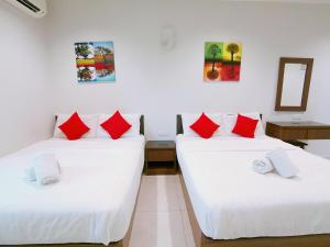 two beds in a room with white and red pillows at HKF Hotel in Kajang