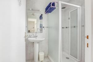 a white bathroom with a shower and a sink at Gite Barbey in Sainte-Marie-du-Mont