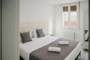 a bedroom with a white bed with two pillows on it at BBarcelona Fira Superior Flats in Barcelona