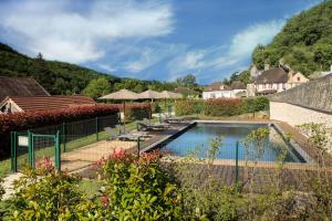 a swimming pool with chairs and umbrellas at Comtesse de Dordogne in Les Eyzies-de-Tayac