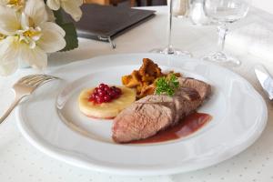 a plate of food with meat and fruit on a table at Logis Hotel-Restaurant De La Poste in Urmatt
