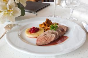 a plate of food with meat and fruit on a table at Hotel-Restaurant De La Poste in Urmatt