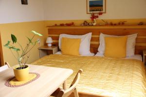 ein Schlafzimmer mit einem Bett mit gelben Kissen und einem Tisch in der Unterkunft Mekina Guesthouse in Maribor