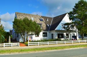 a white house with a black roof and a white fence at Hotel Das kleine Glück - Adults Only in Sankt Peter-Ording