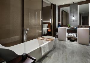HUALUXE Nanjing Yangtze River, an IHG Hotel في نانجينغ: حمام مع حوض استحمام وغرفة نوم