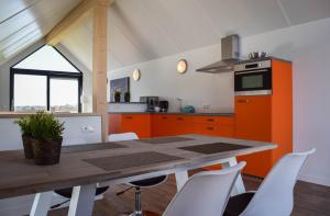 a kitchen with orange cabinets and a table with chairs at Roggebroek 13 in Stavoren