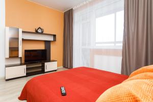 1 dormitorio con TV y 1 cama con manta roja en EtazhiDaily at Studencheskaya, en Yekaterinburg