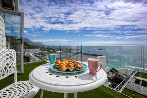 a plate of pastries on a table on a balcony at Clifton YOLO Spaces - Clifton Sea View Apartments in Cape Town