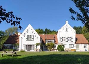 una gran casa blanca con una mesa de picnic delante de ella en B&B Domein Rodin, en Oud-Turnhout