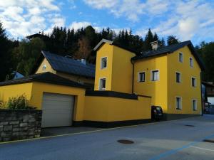 een geel huis met een garage in een straat bij Appartement Tauernlife in Schwarzach im Pongau
