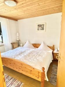 Un dormitorio con una gran cama de madera con sábanas blancas. en Ferienwohnungen Anna Altmann, en Furth im Wald