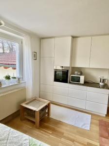 cocina con armarios blancos, mesa y ventana en Ferienwohnungen Anna Altmann, en Furth im Wald